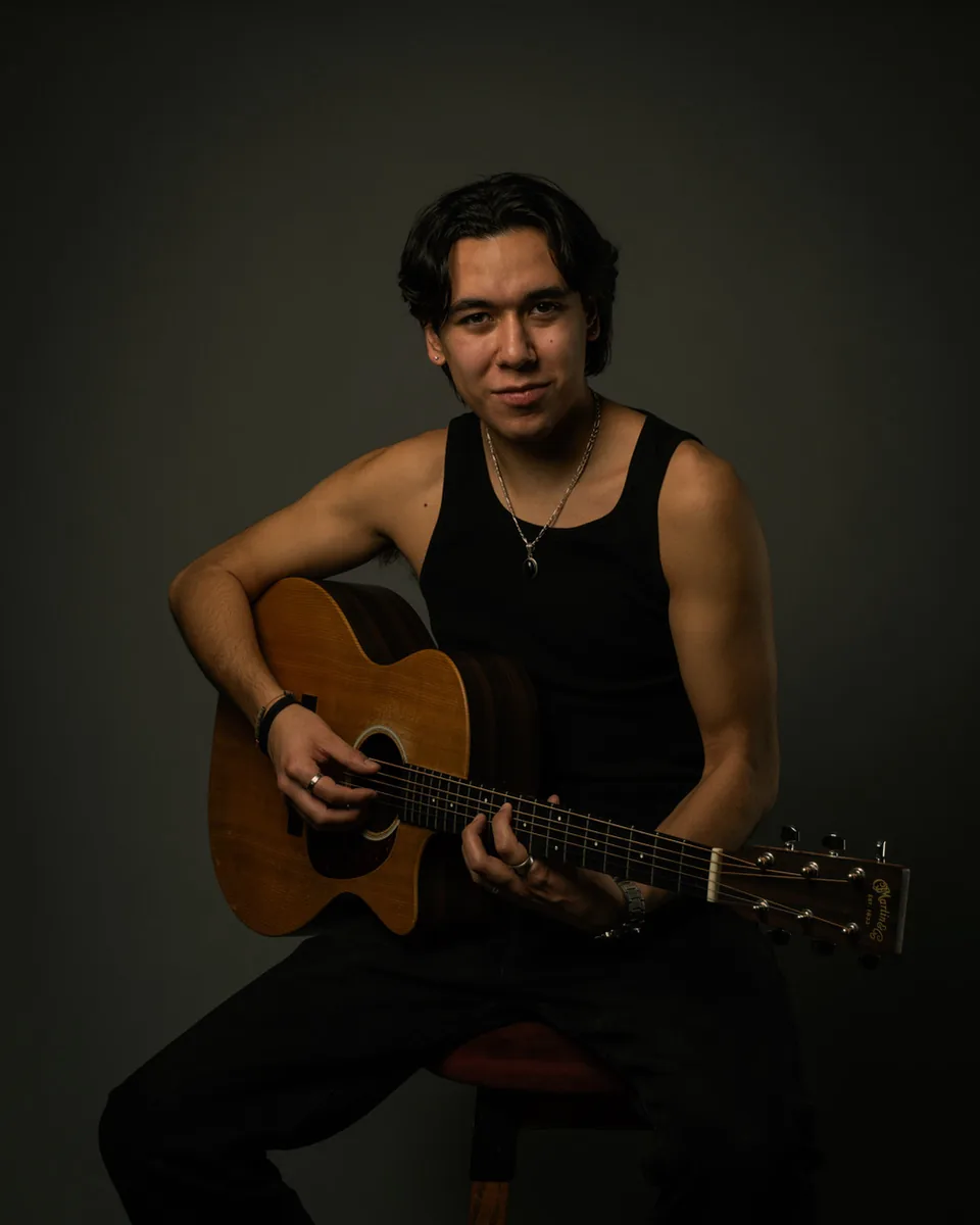 Zeegwon Shilling seated with an acoustic guitar